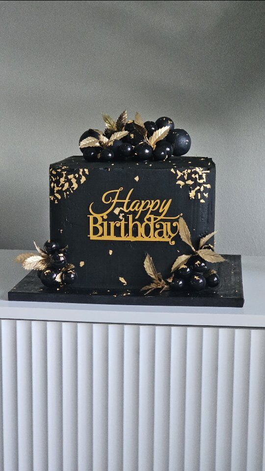 Elegant black and gold birthday cake on a pedestal